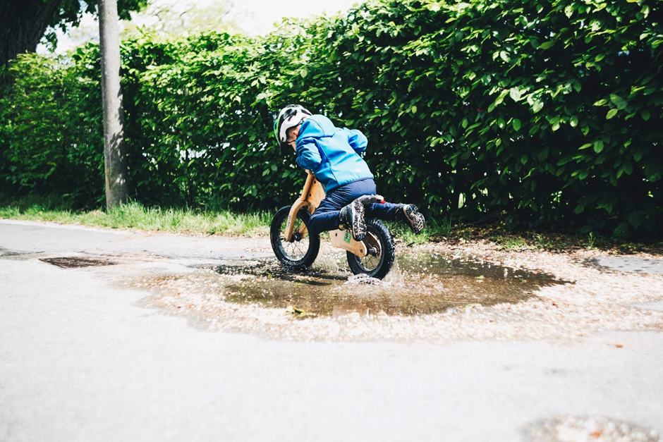A boy riding his bike through a puddle. Photo by Markus Spiske on Unsplash.